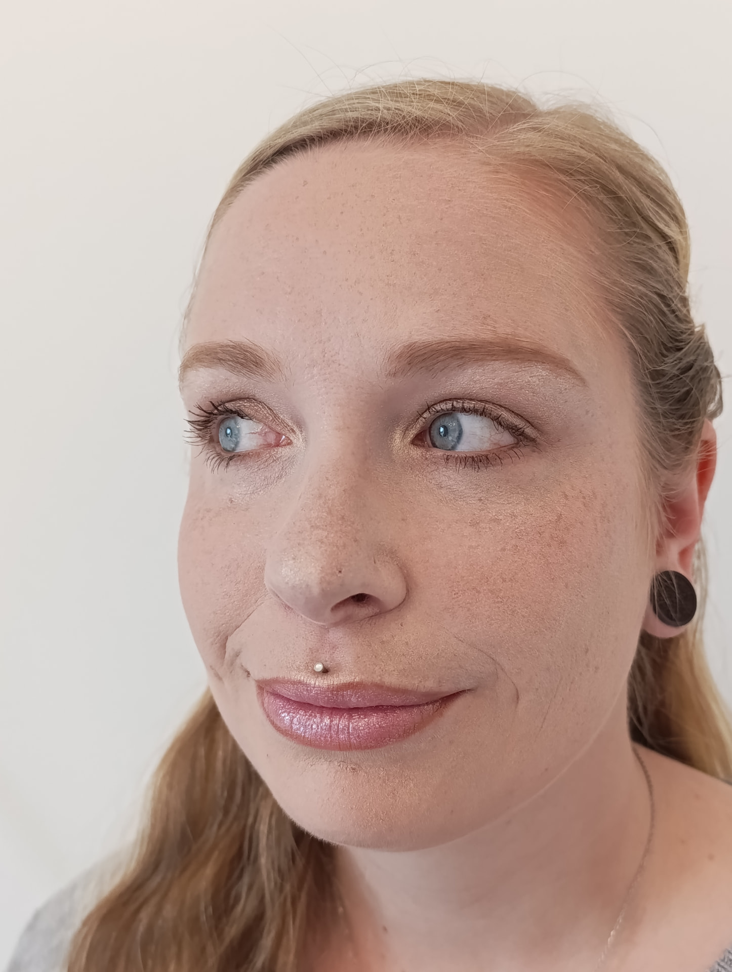 Kundin mit dezentem Make-up, leichtem Goldschimmer auf den Lidern und schimmerndem Rosa-Gloss