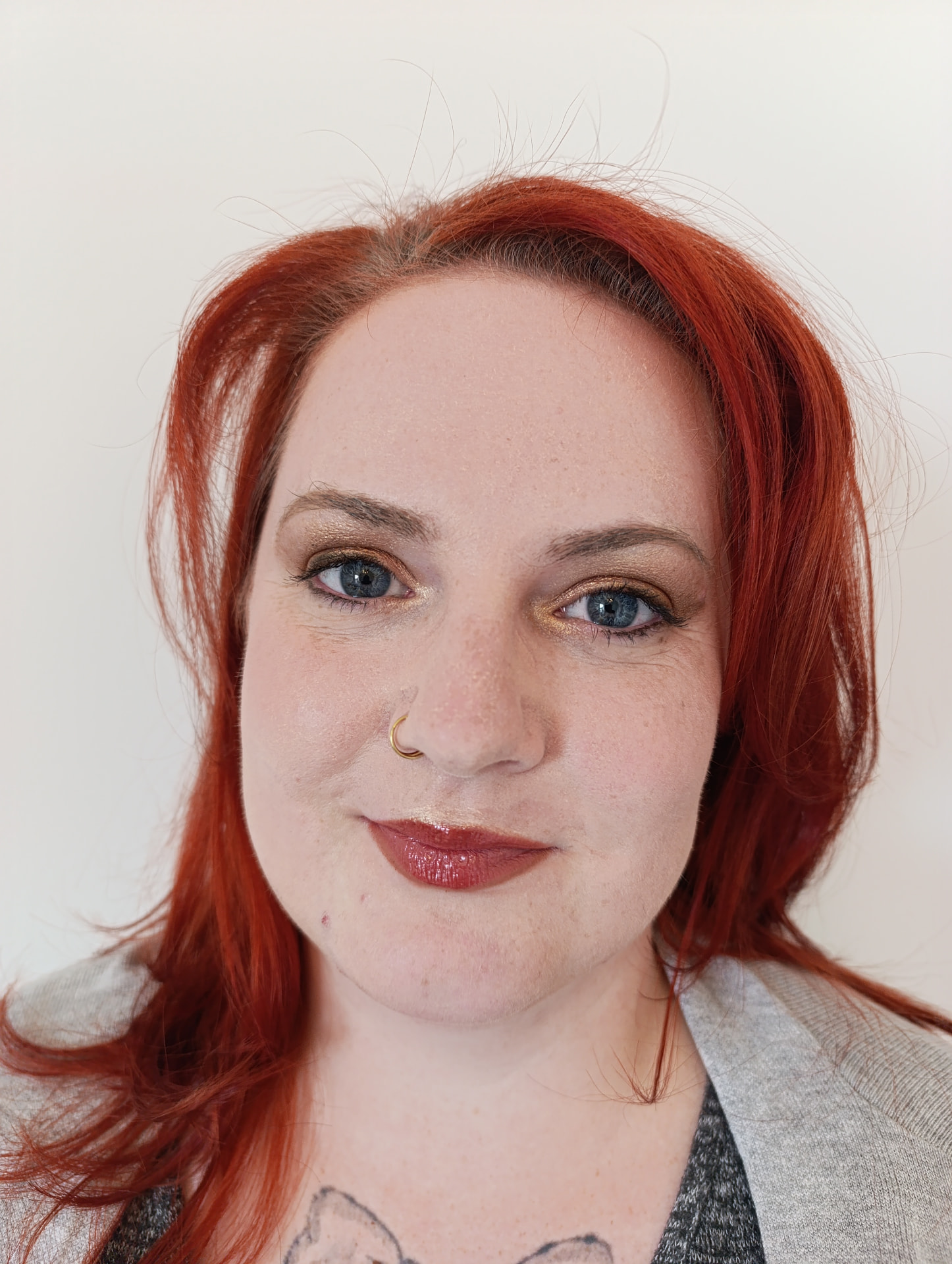 Kundin mit warmem Augen-Make-up in Gold und Bronze, dunklem Lidstrich und rotbraunen Lippen